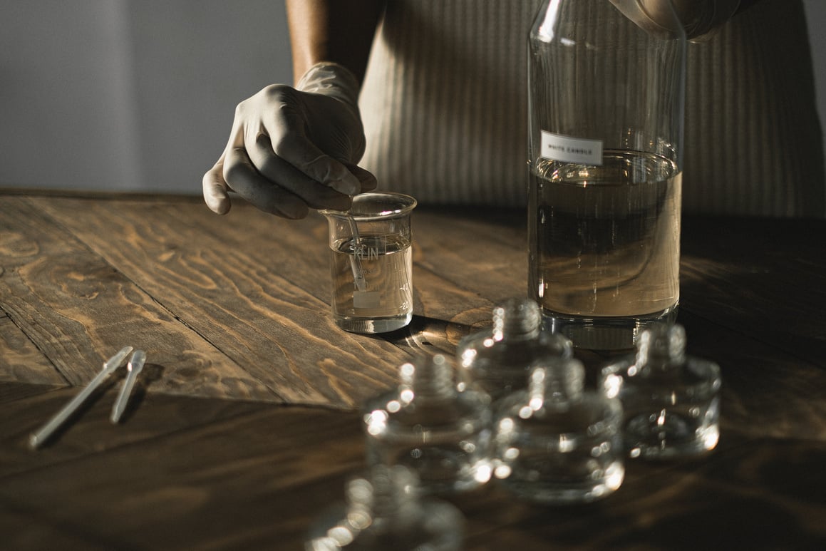 Woman preparing aromatic perfume while mixing fluid in glassware